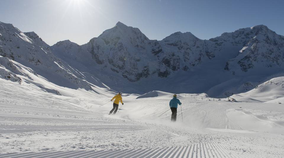 Skifahrer fahren schneebedeckten Ortler herunter in Sulden